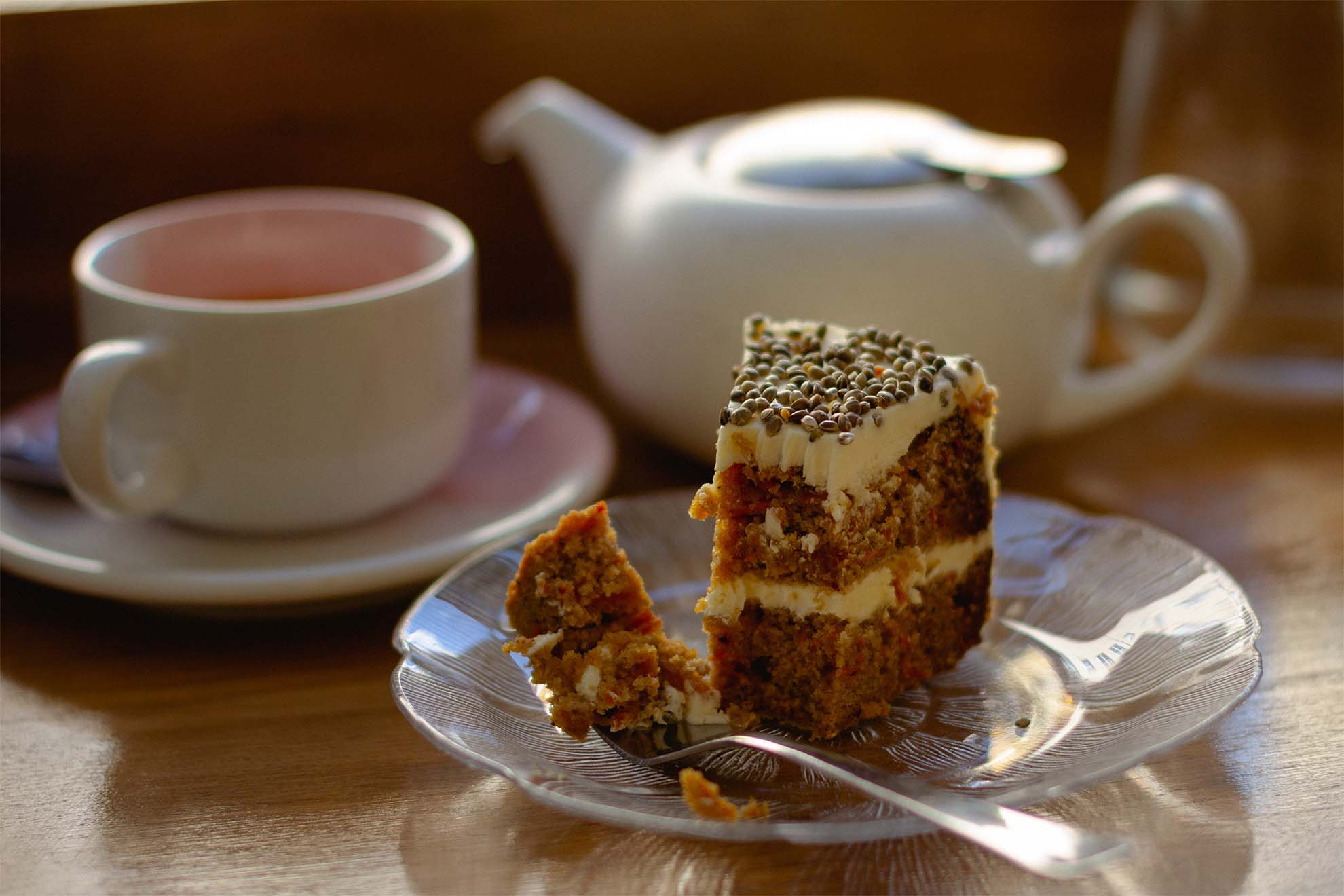a slice of carrot cake with a pot of tea